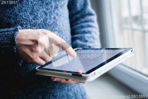 Image of The man uses a tablet PC. Modern gadget in hand.