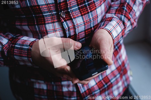 Image of The man is using a smartphone. Modern mobile phone in hand.