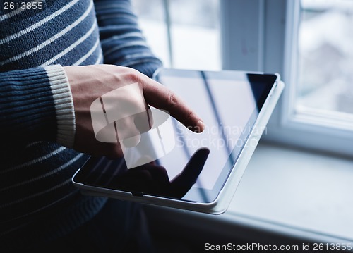 Image of The man uses a tablet PC. Modern gadget in hand.