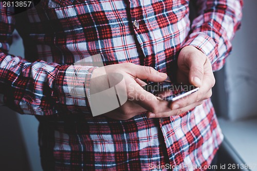 Image of The man is using a smartphone. Modern mobile phone in hand.