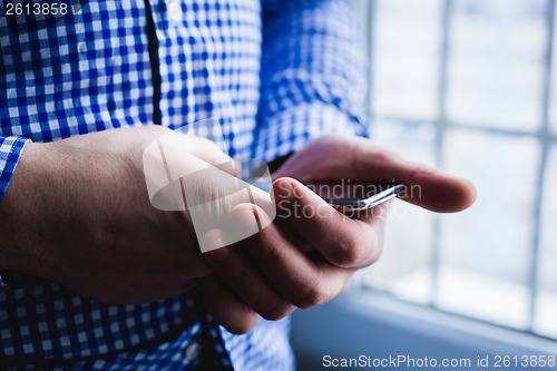 Image of The man is using a smartphone. Modern mobile phone in hand.