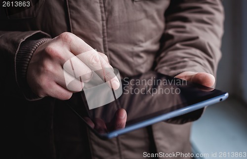 Image of The man uses a tablet PC. Modern gadget in hand.