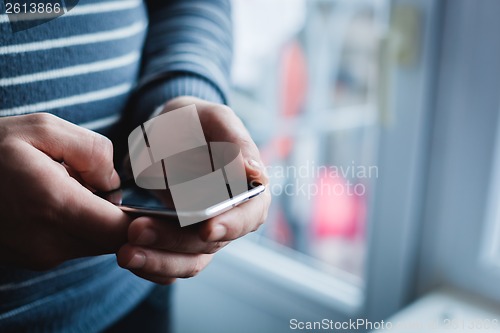 Image of The man is using a smartphone. Modern mobile phone in hand.