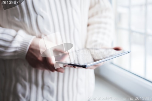 Image of The man uses a tablet PC. Modern gadget in hand.