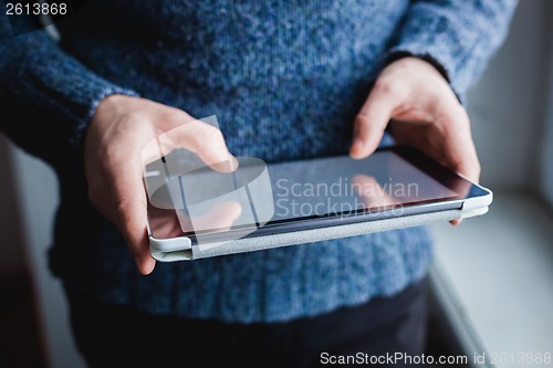 Image of The man uses a tablet PC. Modern gadget in hand.