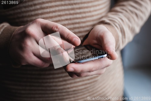 Image of The man is using a smartphone. Modern mobile phone in hand.