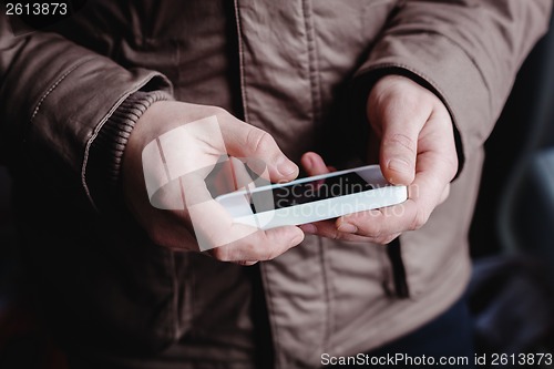 Image of The man is using a smartphone. Modern mobile phone in hand.