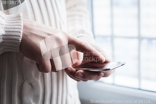 Image of The man is using a smartphone. Modern mobile phone in hand.