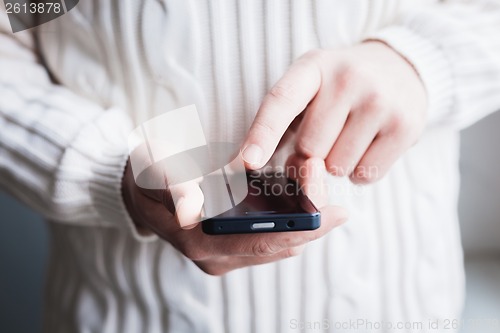 Image of The man is using a smartphone. Modern mobile phone in hand.