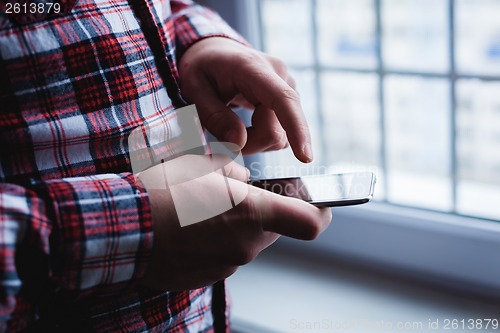 Image of The man is using a smartphone. Modern mobile phone in hand.