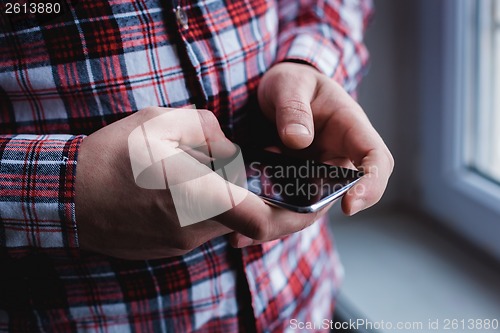 Image of The man is using a smartphone. Modern mobile phone in hand.