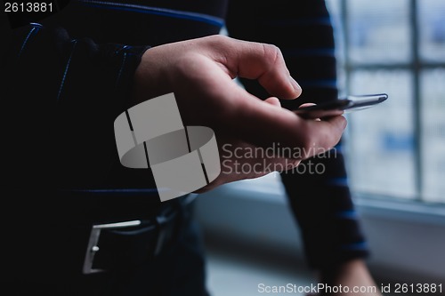 Image of The man is using a smartphone. Modern mobile phone in hand.