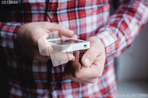 Image of The man is using a smartphone. Modern mobile phone in hand.