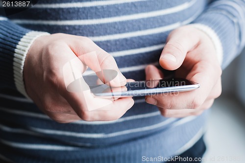 Image of The man is using a smartphone. Modern mobile phone in hand.