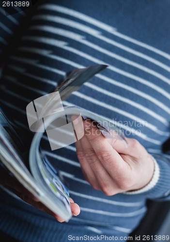 Image of A man looks at a magazine. Press hands.