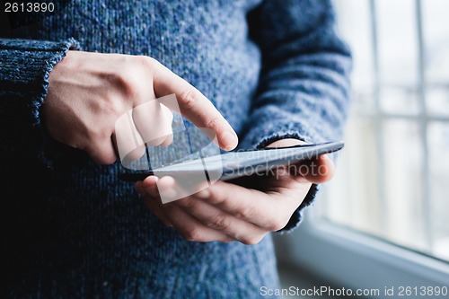 Image of The man uses a tablet PC. Modern gadget in hand.