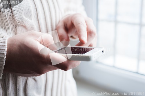 Image of The man is using a smartphone. Modern mobile phone in hand.