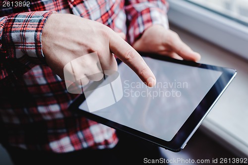 Image of The man uses a tablet PC. Modern gadget in hand.