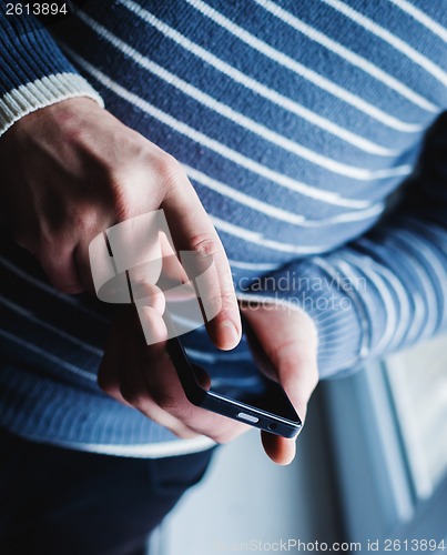 Image of The man is using a smartphone. Modern mobile phone in hand.