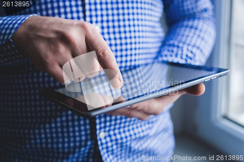 Image of The man uses a tablet PC. Modern gadget in hand.