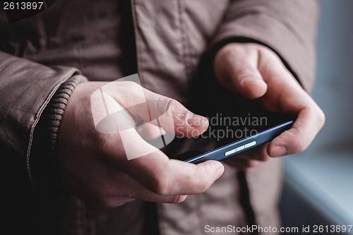 Image of The man is using a smartphone. Modern mobile phone in hand.