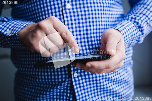 Image of The man uses a tablet PC. Modern gadget in hand.