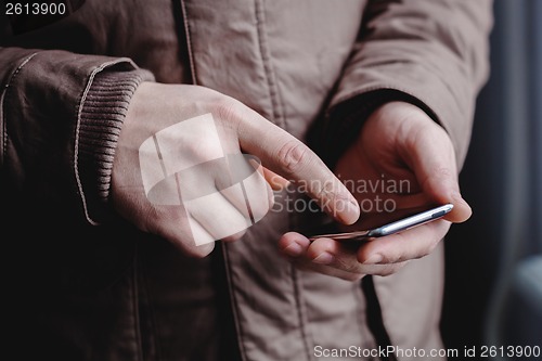 Image of The man is using a smartphone. Modern mobile phone in hand.
