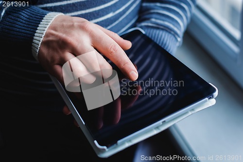 Image of The man uses a tablet PC. Modern gadget in hand.