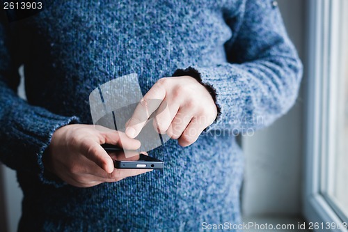 Image of The man is using a smartphone. Modern mobile phone in hand.