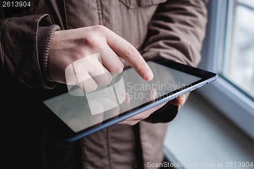 Image of The man uses a tablet PC. Modern gadget in hand.