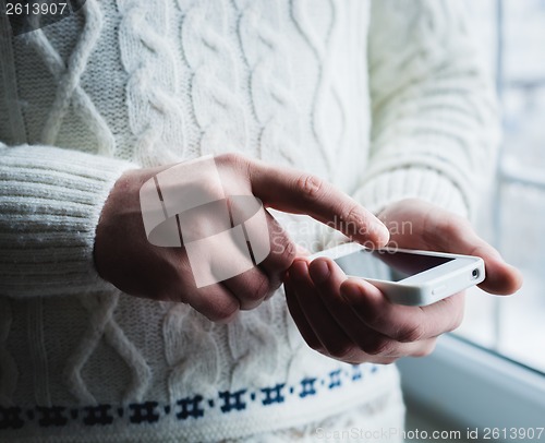 Image of The man is using a smartphone. Modern mobile phone in hand.