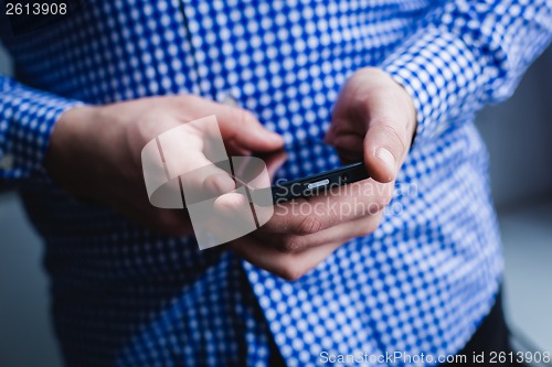 Image of The man is using a smartphone. Modern mobile phone in hand.