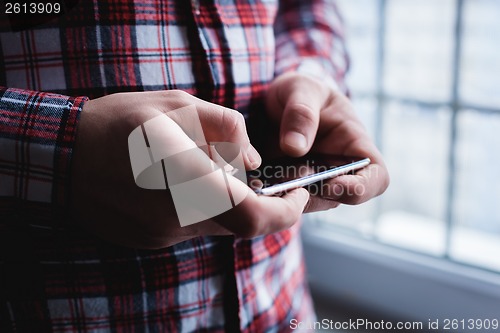 Image of The man is using a smartphone. Modern mobile phone in hand.
