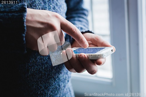 Image of The man is using a smartphone. Modern mobile phone in hand.