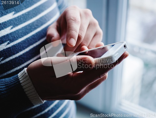 Image of The man is using a smartphone. Modern mobile phone in hand.