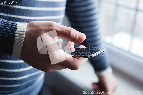 Image of The man is using a smartphone. Modern mobile phone in hand.