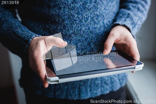 Image of The man uses a tablet PC. Modern gadget in hand.