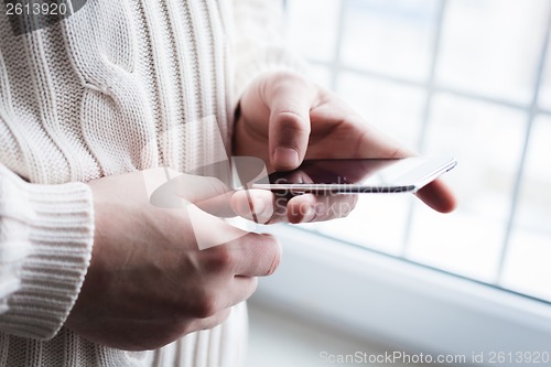 Image of The man is using a smartphone. Modern mobile phone in hand.