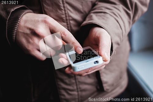 Image of The man is using a smartphone. Modern mobile phone in hand.