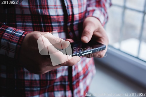 Image of The man is using a smartphone. Modern mobile phone in hand.