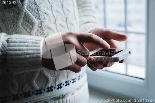 Image of The man is using a smartphone. Modern mobile phone in hand.