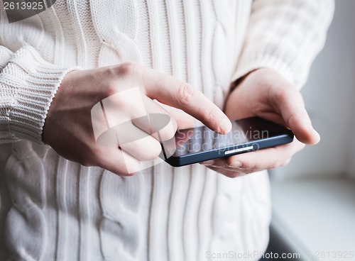 Image of The man is using a smartphone. Modern mobile phone in hand.