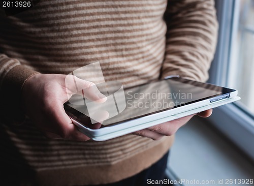 Image of The man uses a tablet PC. Modern gadget in hand.