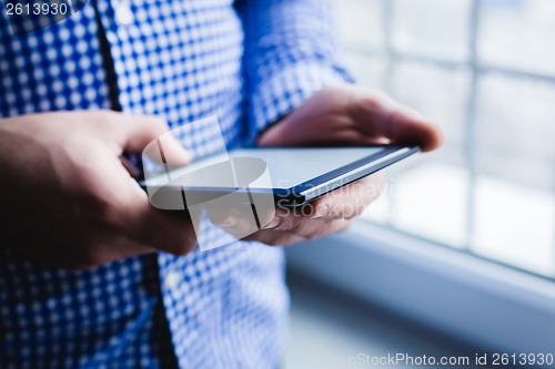 Image of The man uses a tablet PC. Modern gadget in hand.