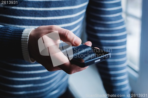 Image of The man is using a smartphone. Modern mobile phone in hand.