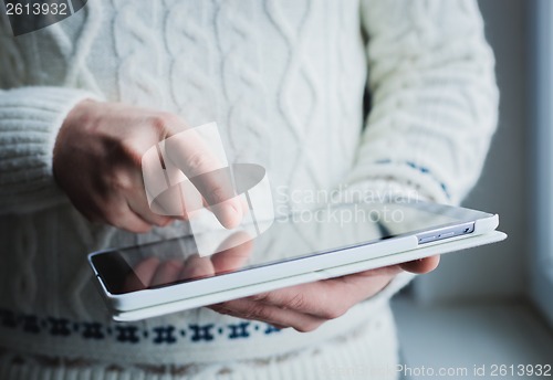 Image of The man uses a tablet PC. Modern gadget in hand.