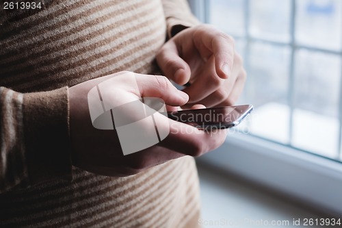 Image of The man is using a smartphone. Modern mobile phone in hand.