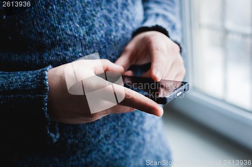 Image of The man is using a smartphone. Modern mobile phone in hand.