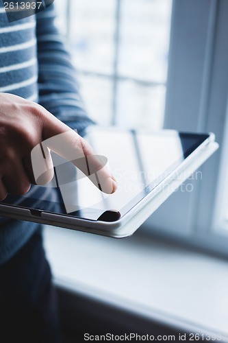 Image of The man uses a tablet PC. Modern gadget in hand.