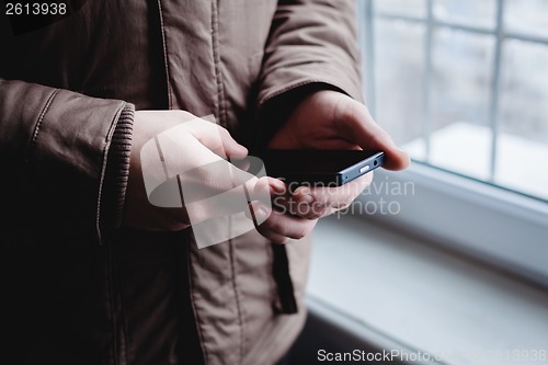Image of The man is using a smartphone. Modern mobile phone in hand.